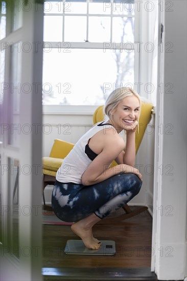 Woman crouching on scale and smiling