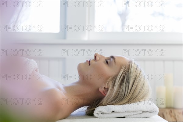 Woman lying on back on massage table with eyes closed