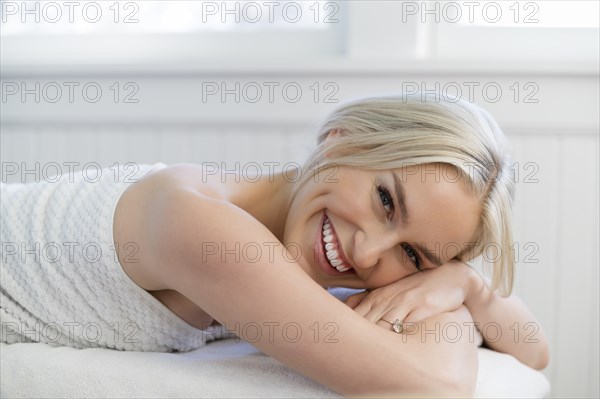 Portrait of young woman with toothy smiling on massage table