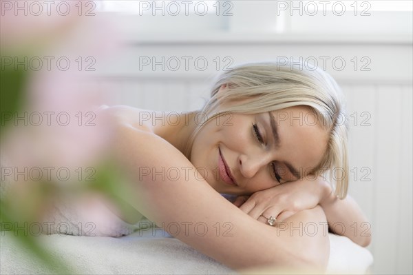 Smiling woman lying with eyes closed on massage table