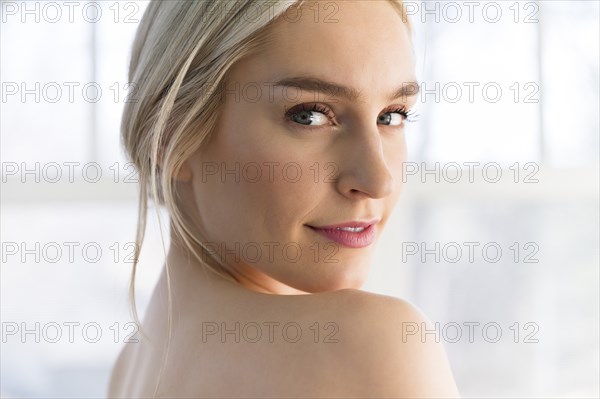 Portrait of woman looking over her bare shoulder