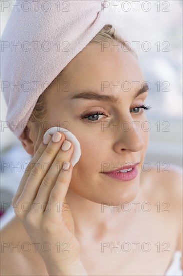 Woman cleaning face with cotton pad