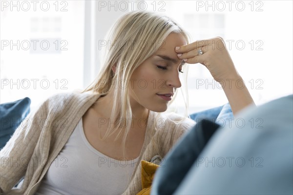 Woman with headache siting on sofa