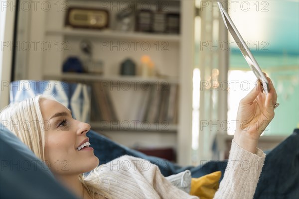 Woman using tablet while lying on sofa