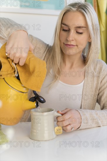Woman making tea, pouring water from kettle