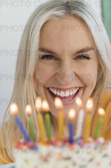 Woman smiling behind birthday candles