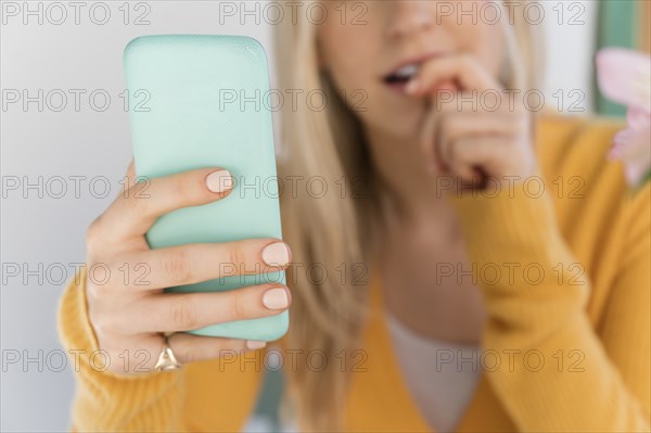 Woman holding smartphone and biting nails