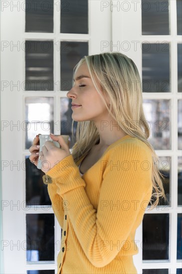 Portrait of woman in yellow sweater holding mug