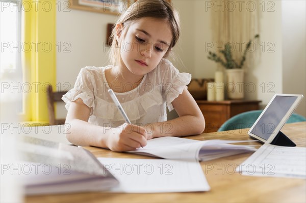 Girl (6-7) working on schoolwork at home