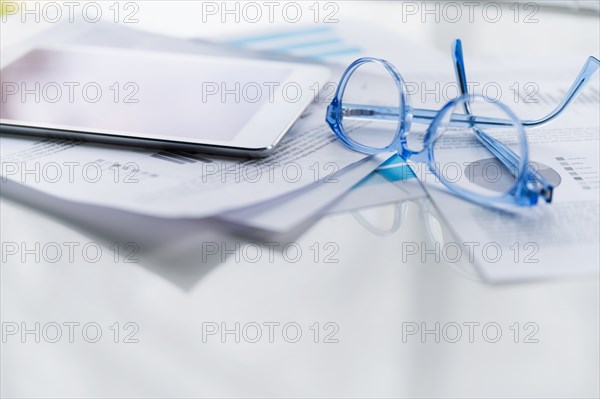 Blue eyeglasses and tablet on business papers