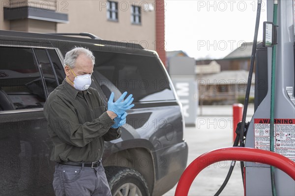 Man wearing surgical gloves and mask at gas station