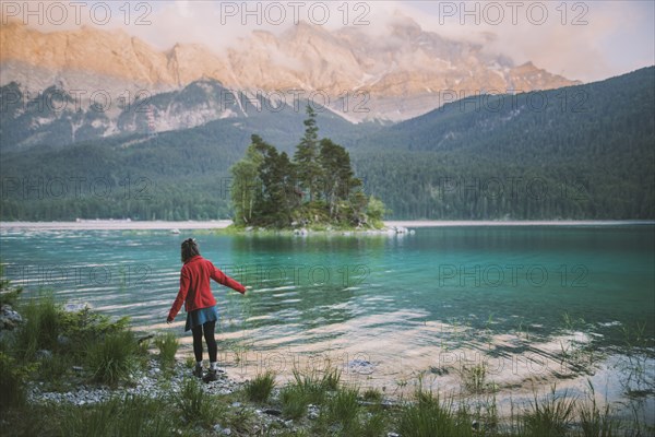 Germany, Bavaria, Eibsee, Young woman walking at shore of Eibsee lake in Bavarian Alps