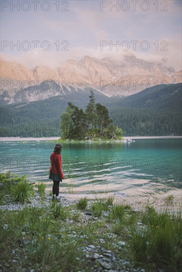 Germany, Bavaria, Eibsee, Young woman standing at shore of Eibsee lake in Bavarian Alps