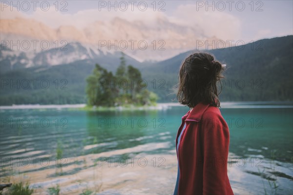 Germany, Bavaria, Eibsee, Young woman standing at by Eibsee lake in Bavarian Alps and looking at view