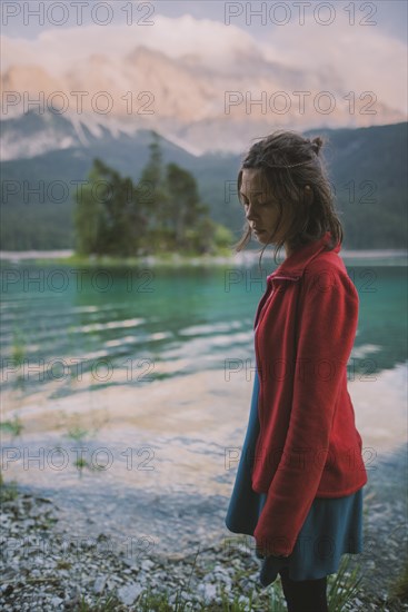 Germany, Bavaria, Eibsee, Young woman standing at shore of Eibsee lake in Bavarian Alps