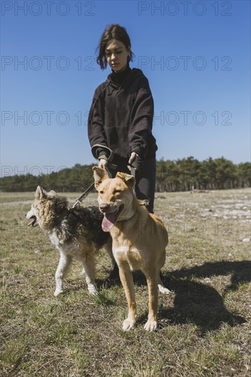 Young woman walking with dogs from animal shelter