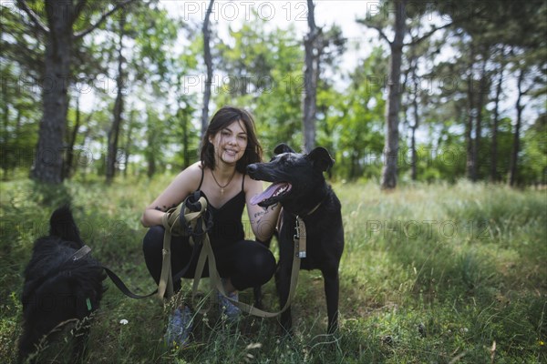 Young woman walking dogs from animal shelter in pine forest