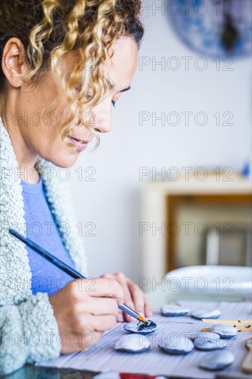 Woman painting stones at home