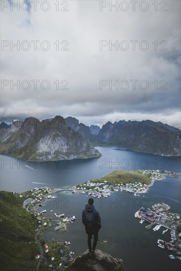 Norway, Lofoten Islands, Reine, Man looking at fjord from Reinebringen mountain