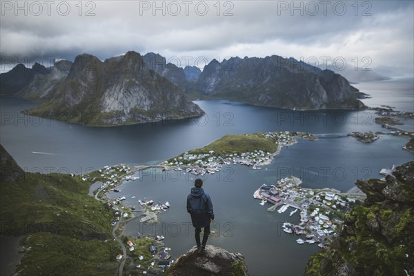 Norway, Lofoten Islands, Reine, Man looking at fjord from Reinebringen mountain