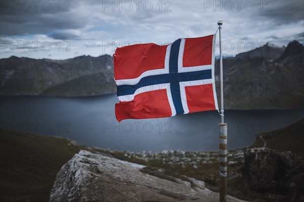 Norway, Senja, Norwegian flag with fjord and mountains in background