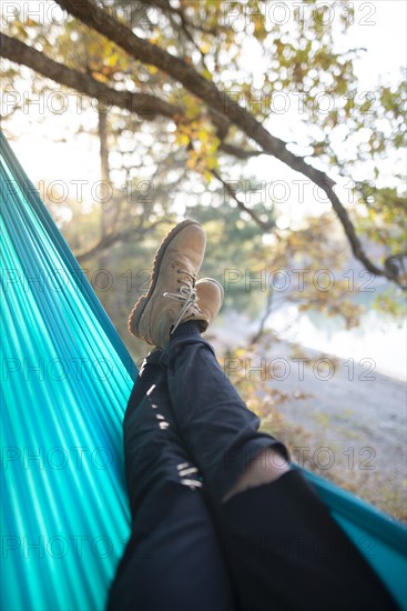 Italy, Man lying in hammock near lake