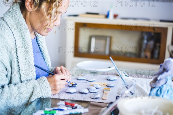 Woman painting stones at home