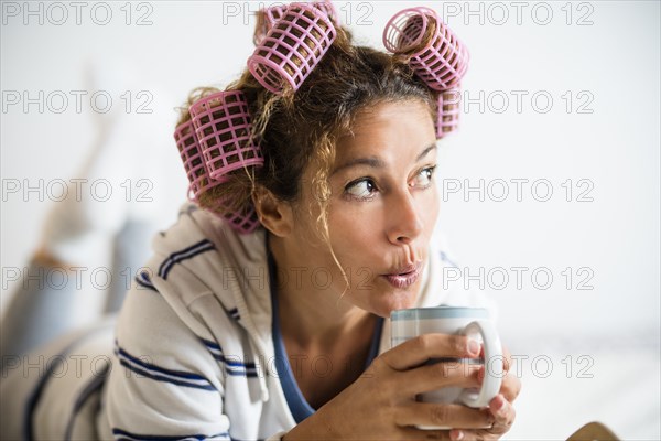Woman with hair curlers holding mug