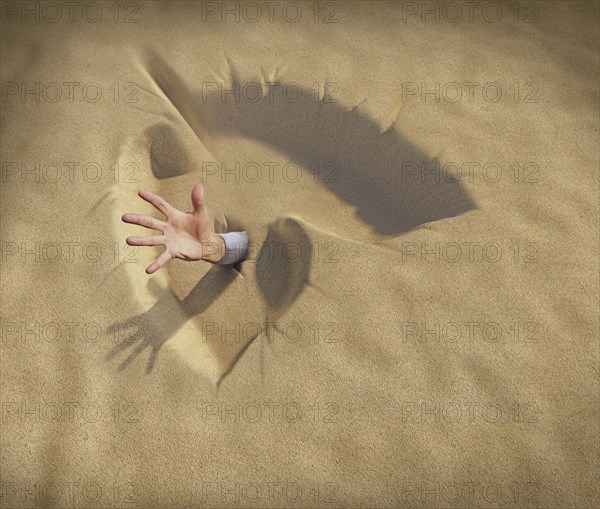 Hand reaching from lungs shaped sand