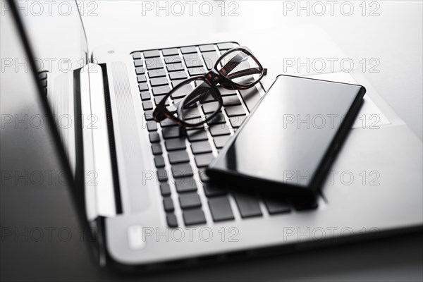 Smart phone and glasses on laptop keyboard