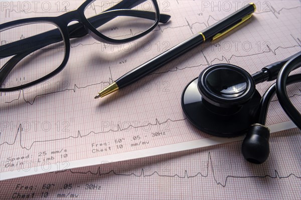 Stethoscope, glasses and pen on electrocardiogram