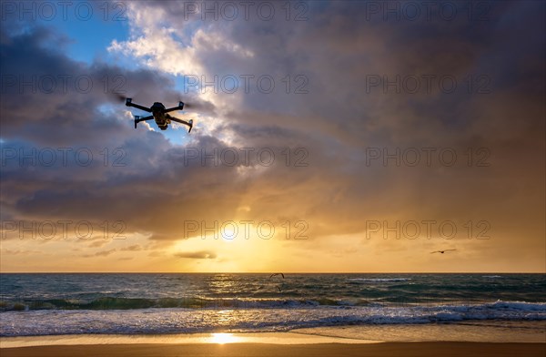 Drone flying over beach at sunset