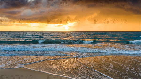 Beach under dramatic sky at sunset