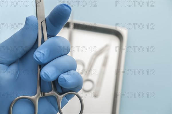 Person wearing latex glove holding forceps