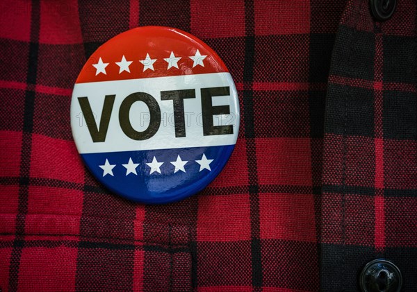 Vote button on red checked shirt