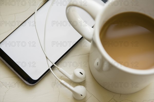 Earphones, smart phone and cup of coffee