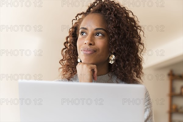 Woman thinking behind laptop