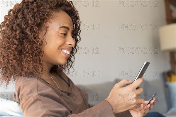 Smiling woman holding credit card and smart phone