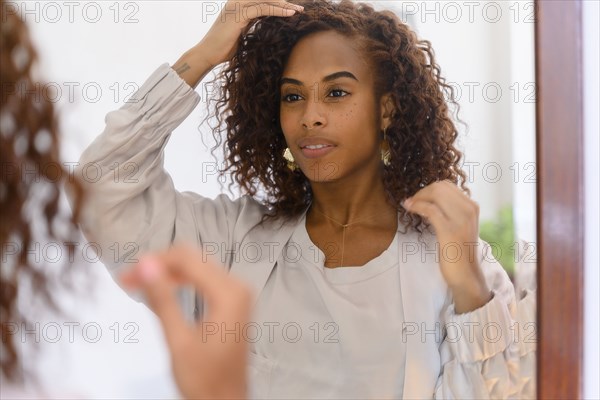 Woman adjusting hair in mirror