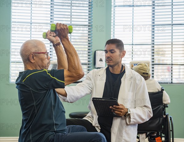 Senior man lifting dumbbells at rehabilitation center