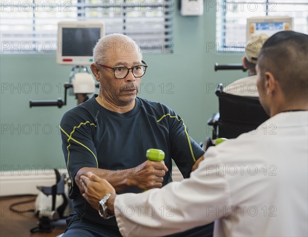 Senior man lifting dumbbells at rehabilitation center