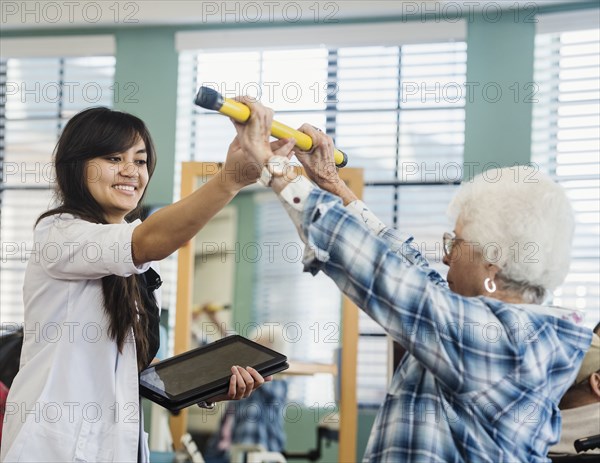 Smiling doctor helping senior woman hold pole