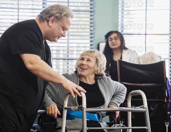 Nurse helping smiling senior woman use walking frame