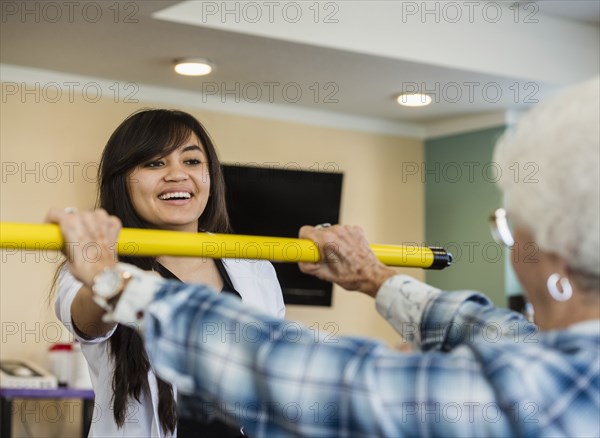 Smiling doctor helping senior woman hold pole