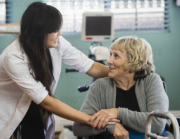 Smiling doctor and senior woman holding hands at rehabilitation center