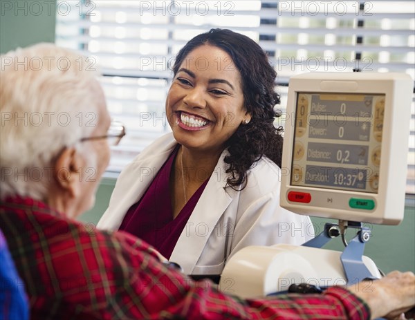 Smiling doctor and senior man by machine monitor