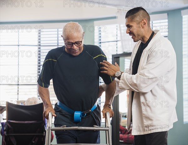 Doctor helping senior man use walking frame