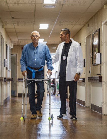 Doctor helping senior man use walking frame