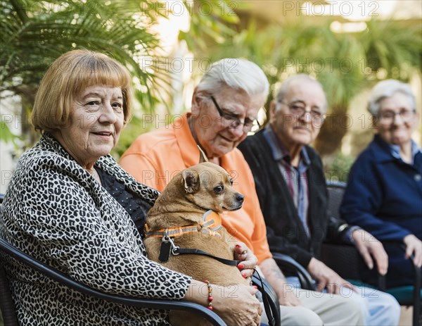 Senior people sitting in chairs with dog