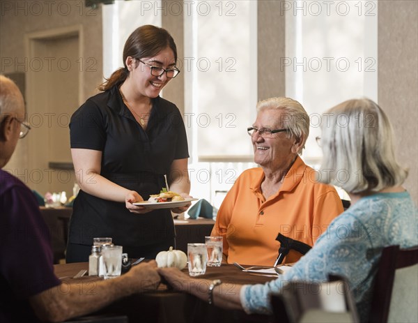 Smiling waitress handing food to smiling senior man